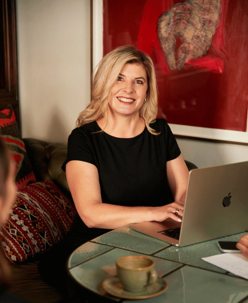Smiling woman working on laptop while sitting on leather sofa.