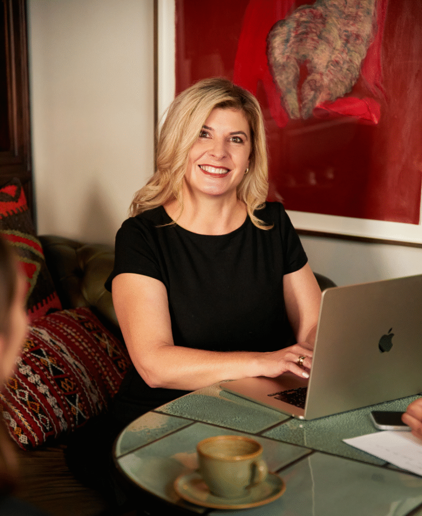 Smiling woman working on laptop while sitting on leather sofa.